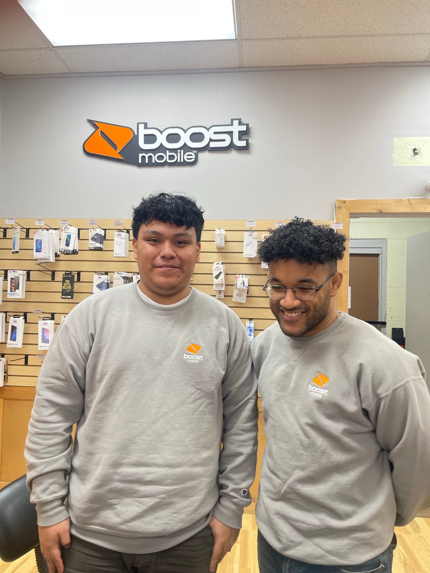 Two RBFC teammates together in front of the Boost Mobile logo inside a store
